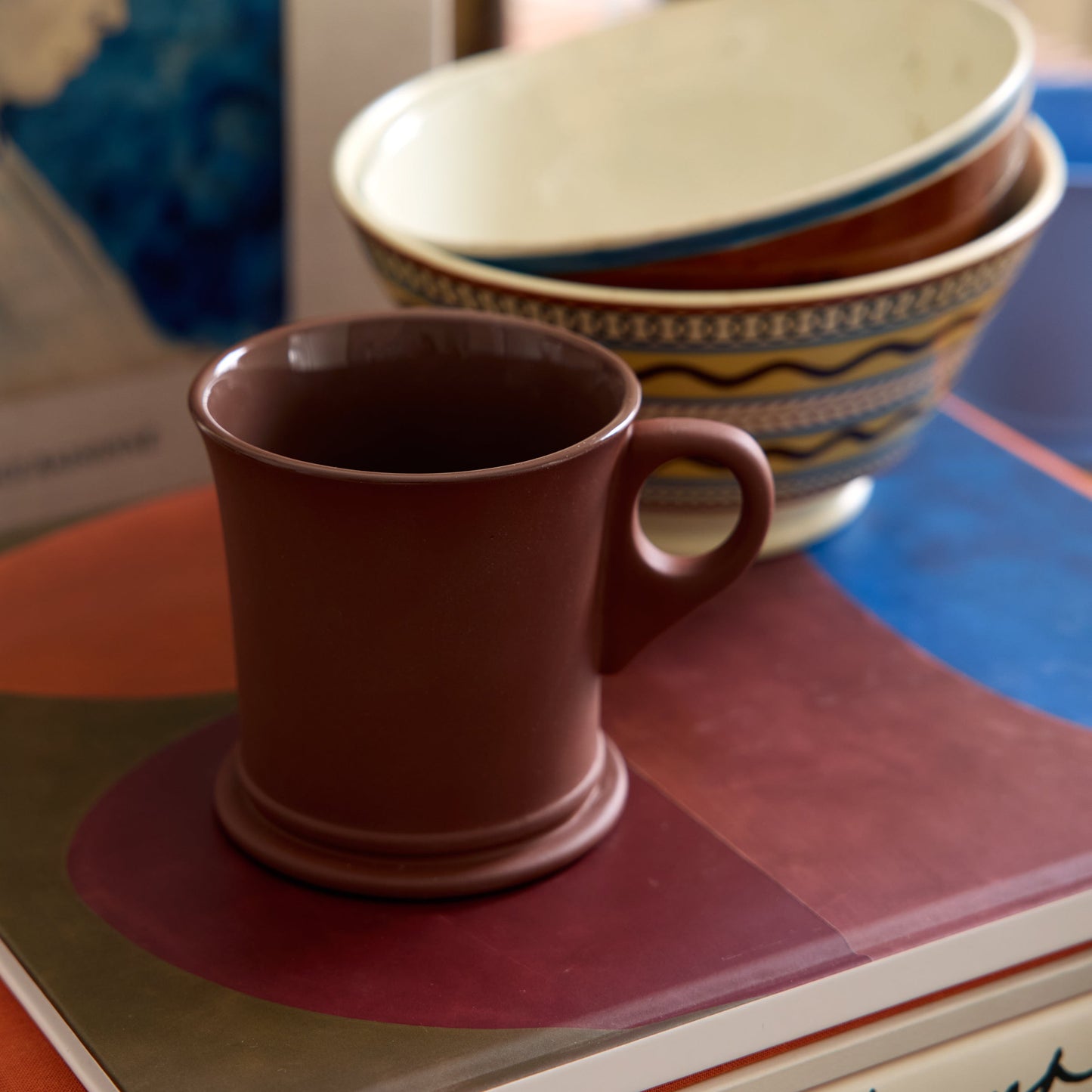 Brown mug on a stack of books with bowls in the background