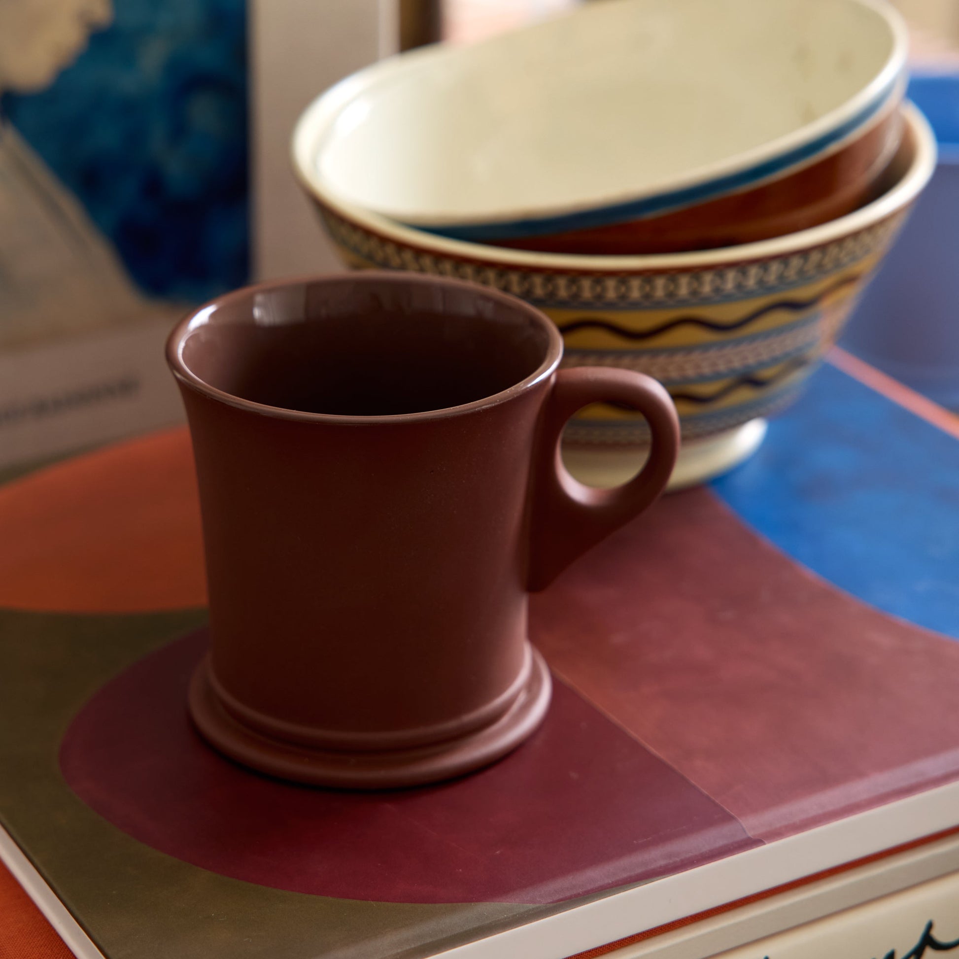 Brown mug on a stack of books with bowls in the background